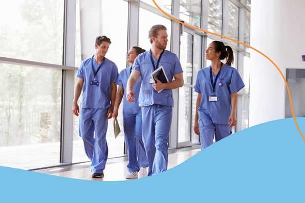 A group of clinicians in blue scrubs walking through a well-lit facility hallway, representing coordinated care in long-term and post-acute care settings.
